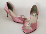 A pair of dusty rose satin medium height heel shoes with a peep toe and designed with a crystal design on the front of the shoes