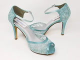 A pair of blue lace high heeled shoes with a front hidden platform and an ankle strap with a peep toe