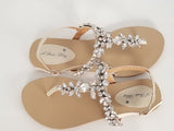 a pair of flat heel ivory bridal sandals with crystals on the straps of the sandals