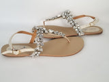 a pair of flat heel ivory bridal sandals with crystals on the straps of the sandals