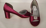 A pair of burgundy shoes with a low block heel and a peep toe front with a crystal design on the front of the shoes