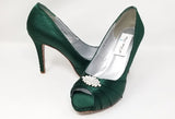 A pair of high heeled hunter green satin shoes with a peep toe and a hidden platform at the front of the shoes and a crystal design on the front of the shoes