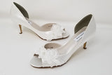 A pair of white satin wedding heels with a peep toe and designed with an all over lace design with pearls