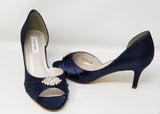 A pair of navy medium height heel shoes with a peep toe and designed with a crystal design on the front of the shoes