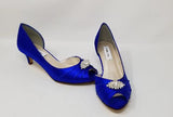 A pair of royal blue satin kitten heel shoes with a peep toe with a small crystal design on the front of the shoes