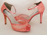 A pair of coral lace high heeled shoes with a front hidden platform and an ankle strap with a peep toe