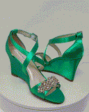 A pair of emerald green wedding shoes with high wedge and straps across the front of the foot designed with a rose gold crystal design on the front toe strap of the shoes