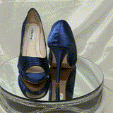 A pair of high heeled navy blue satin shoes with a peep toe and a hidden platform at the front of the shoes