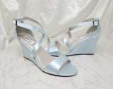 A pair of baby blue wedding shoes with high wedge and straps across the front of the foot