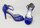 A pair of royal blue lace high heeled shoes with a front hidden platform and an ankle strap with a peep toe