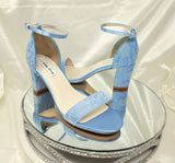 A pair of blue lace covered low block heel shoes with an ankle strap