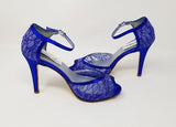 A pair of royal blue lace high heeled shoes with a front hidden platform and an ankle strap with a peep toe