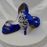 A pair of royal blue satin medium height heel bridal shoes with a peep toe and designed with a crystal design on the front of the shoes and a crystal design on the back heel of the shoes