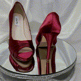 A pair of high heeled burgundy satin shoes with a peep toe and a hidden platform at the front of the shoes