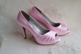 A pair of high heeled pink satin shoes with a peep toe and a hidden platform at the front of the shoes