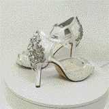 A pair of white high heeled platform lace shoes with an ankle strap and a crystal design on the front of the peep toe shoes and a crystal design on the back heel of the shoes