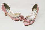 A pair of dusty rose satin kitten heels with a peep toe and designed with a crystal design on the front of the shoes