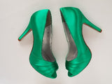 A pair of high heeled emerald green satin shoes with a peep toe and a hidden platform at the front of the shoes