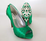 A pair of high heeled emerald green satin shoes with a peep toe and a hidden platform at the front of the shoes and a crystal design on the back heel of the shoes