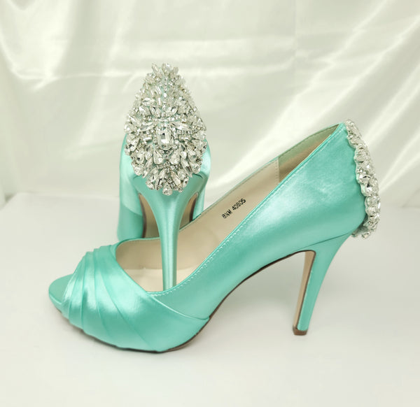 A pair of high heeled aqua blue satin shoes with a peep toe and a hidden platform at the front of the shoes and a crystal design on the front of the shoes and a crystal design on the back heel of the shoes