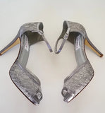 A pair of gray lace high heeled shoes with a front hidden platform and an ankle strap with a peep toe