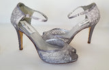 A pair of gray lace high heeled shoes with a front hidden platform and an ankle strap with a peep toe