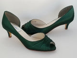 A pair of hunter green low heel satin kitten heel shoes with a peep toe
