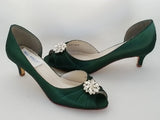 A pair of hunter green satin kitten heels with a peep toe and designed with a crystal design on the front of the shoes