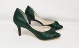 A pair of hunter green satin medium height heel shoes with a peep toe