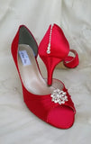 A pair of red satin medium height heel shoes with a peep toe and designed with a crystal design on the front of the shoes and a crystal design on the back heel of the shoes