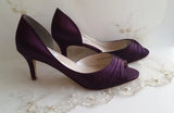 A pair of eggplant purple satin medium height heel shoes with a peep toe