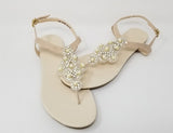 a pair of flat heel ivory bridal sandals with pearls and crystals on the straps of the sandals