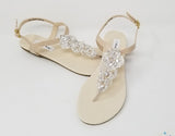 a pair of flat heel ivory bridal sandals with crystals on the straps of the sandals
