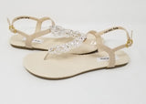 a pair of flat heel ivory bridal sandals with crystals on the straps of the sandals