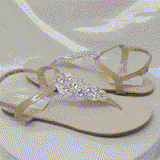 a pair of flat heel ivory bridal sandals with crystals on the straps of the sandals