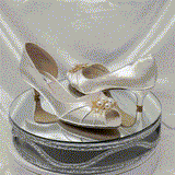 A pair of  bridal shoes in ivory satin with a kitten heel and a peep toe and a gold pearl and crystal design on the front of the shoes