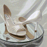 A pair of ivory satin medium height heel shoes with a peep toe