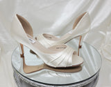 A pair of ivory satin medium height heel shoes with a peep toe