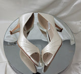 A pair of ivory satin medium height heel shoes with a peep toe