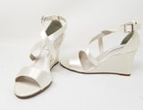 A pair of ivory wedding shoes with high wedge and straps across the front of the foot