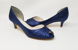 A pair of navy blue low heel satin kitten heel shoes with a peep toe