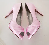 A pair of high heeled pink satin shoes with a peep toe and a hidden platform at the front of the shoes