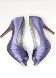A pair of high heeled lilac purple satin shoes with a peep toe and a hidden platform at the front of the shoes
