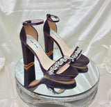 a pair of high heel block shoes dyed eggplant purple with a sparkling crystal design on the front toe strap