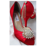 A pair of red satin medium height heel shoes with a peep toe and designed with a crystal design on the front of the shoes and a crystal design on the back heel of the shoes