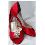 A pair of red satin medium height heel shoes with a peep toe and designed with a crystal design on the front of the shoes