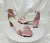 A pair of dusty rose block heel shoes with an ankle strap