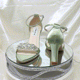 A pair of sage green block heel shoes with an ankle strap and a crystal design on the front toe strap