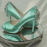 A pair of high heeled aqua blue satin shoes with a peep toe and a hidden platform at the front of the shoes and a crystal design on the front of the shoes and a crystal design on the back heel of the shoes