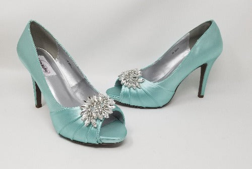 A pair of high heeled aqua blue satin shoes with a peep toe and a hidden platform at the front of the shoes and a crystal design on the front of the shoes